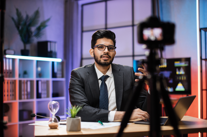 Confident indian bearded businessman in suit sitting in front of camera after learning what is cornerstone content in evening office